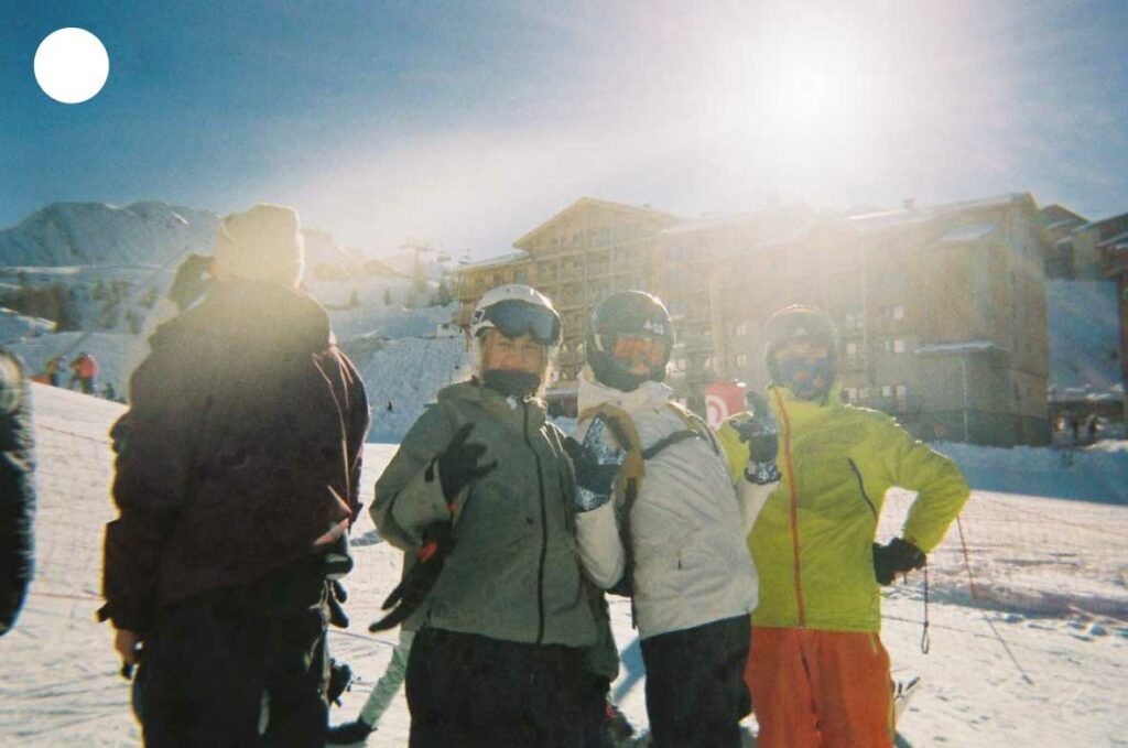 Groupe d’amis posant en combinaisons de ski sur les pistes enneigées, incarnant l’esprit convivial des sports d’hiver.
