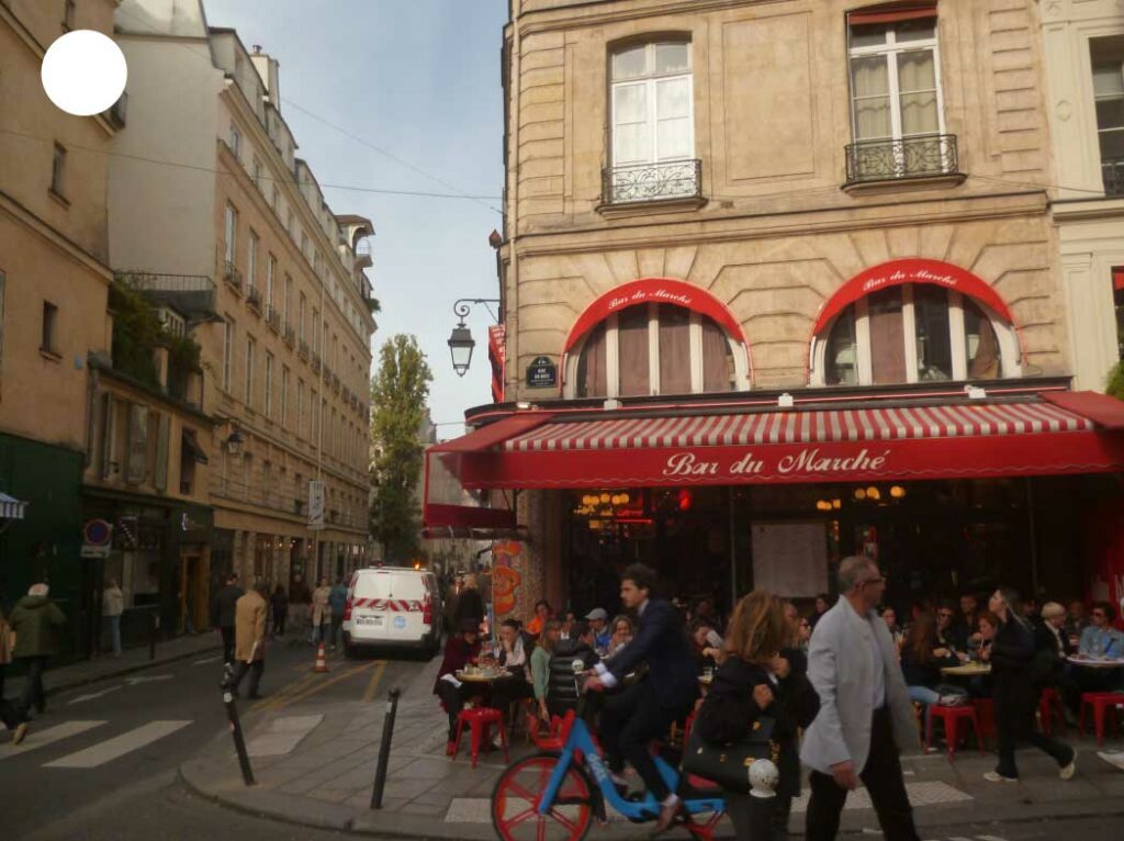 Rue passante animée devant un café à Paris, capturant l’atmosphère vivante et authentique de la capitale.
