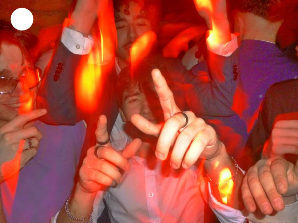 Personnes dansant et faisant la fête sous des lumières rouges intenses, capturant l’énergie vibrante et l’ambiance nocturne festive.