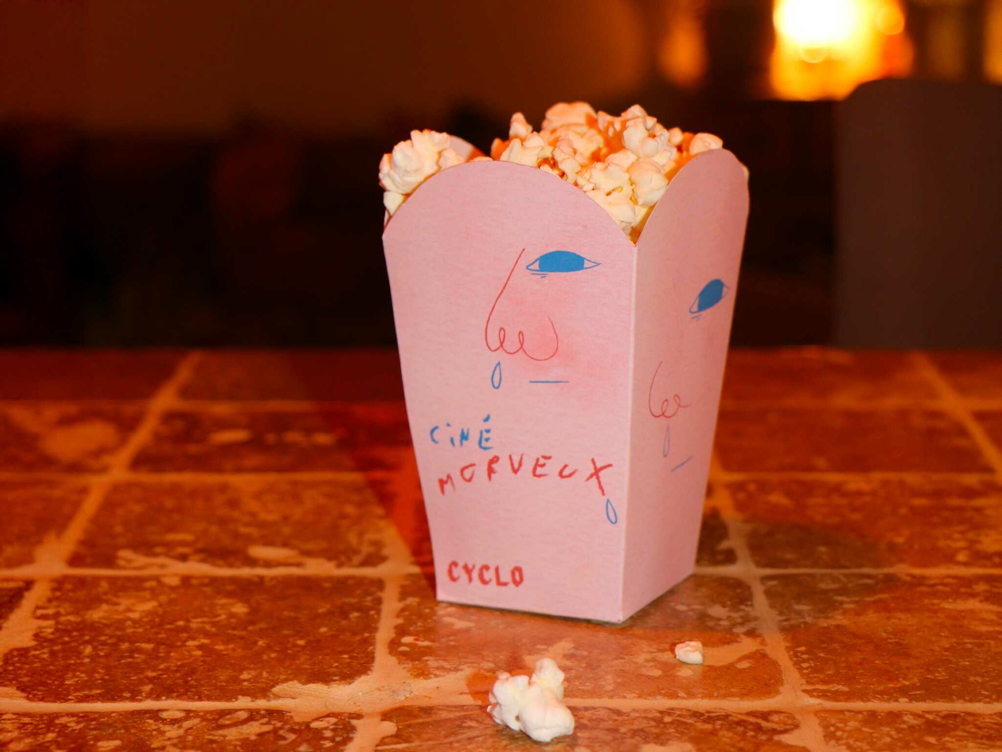 Photographie des paquets de pop-corn rose pour le cinéma Morveux avec le design du visage d’enfant morve au nez et ambiance colorée.