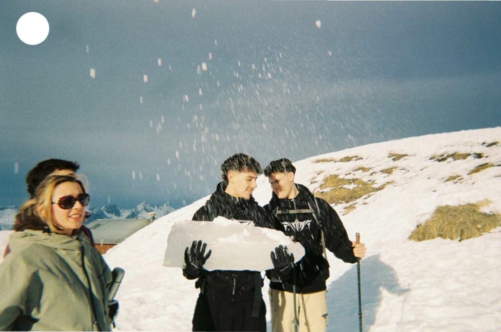 Trois amis transportant un glaçon géant sur la neige, une scène insolite et dynamique au cœur d’un décor hivernal.